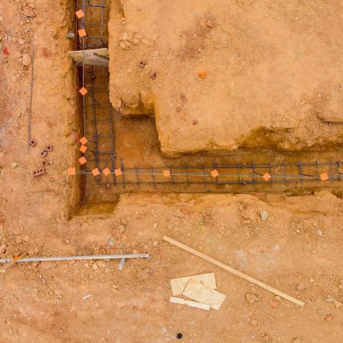 Performing works of putting steel in a trench for a house foundation on a construction site