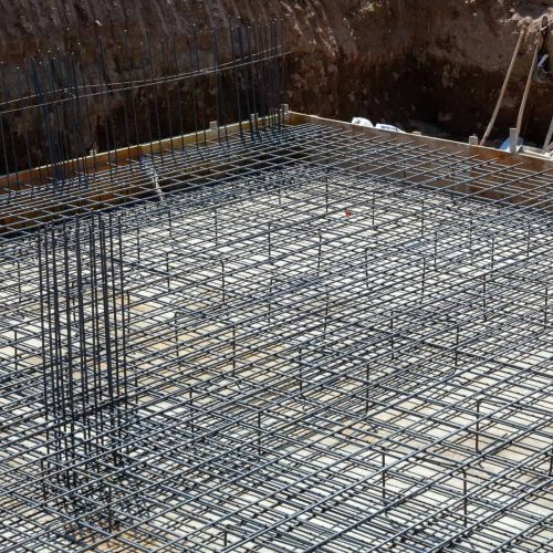 Steel rebar grid forming foundation structure at construction site